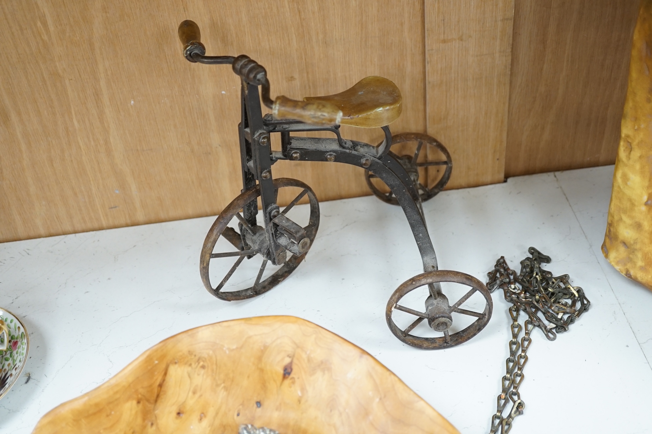 A cast iron toy model of a tricycle, a carved wooden bow, a classical figurative door knocker, a pair of metal cow shoes and two ceramic cistern pulls, bowl 30cm diameter. Condition - fair